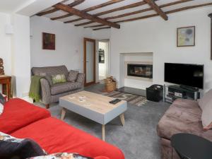 a living room with a red couch and a fireplace at Holly Tree Cottage in Chester