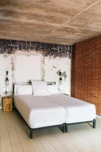 Cama blanca en habitación con pared de ladrillo en Barcelona Apartment Republica en Barcelona