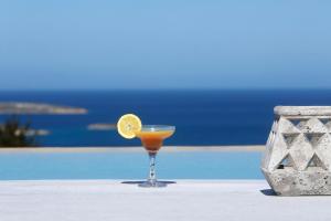 un drink seduto su un tavolo accanto alla piscina di Angels Estate Precious Villas a Naoussa