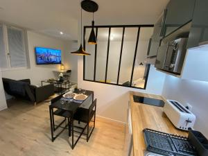 a kitchen and living room with a table and a couch at Le Standing - Au Coeur d'Agen - Self Checkin - Wifi - Netflix - Smart TV - Luqs fr in Agen