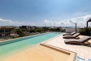 a swimming pool on top of a building with chairs at Riva 202 Playa del Carmen Condo in Playa del Carmen