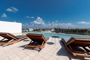 a swimming pool with two chairs and a table on a roof at Riva 202 Playa del Carmen Condo in Playa del Carmen