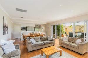 a living room with two couches and a table at Ocean Keys Cottage - Free WiFi in Mindarie