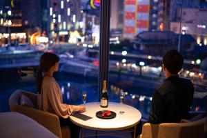 福岡的住宿－The OneFive Villa Fukuoka，坐在桌子旁的男人和女人,喝一瓶葡萄酒