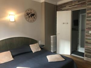 - une chambre dotée d'un lit avec une horloge murale dans l'établissement Hotel Bernieres, à Caen