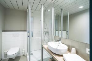 a bathroom with a toilet, sink, and shower at WIROtel Mittelmole in Warnemünde