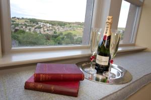 una bottiglia di vino, due bicchieri e un libro di The Fleece Inn a Haworth