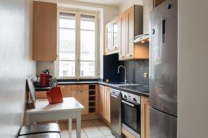 uma pequena cozinha com armários de madeira e uma janela em DIFY Universités - Bord du Rhône em Lyon