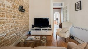 uma sala de estar com uma televisão, um sofá e uma cadeira em DIFY Universités - Bord du Rhône em Lyon