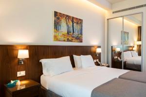 a hotel room with a large white bed and a mirror at Citea Apart Hotel in Beirut