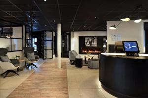 a lobby with a bar and chairs and a fireplace at Gr8 Hotel Amsterdam Riverside in Amsterdam