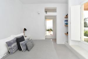 Habitación blanca con sofá y almohadas. en Thiro Santorini, en Fira