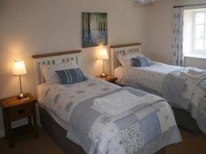 two beds in a room with two lamps on tables at Derwent Cottage in Malton