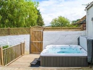 een hot tub op een terras naast een hek bij Derwent Cottage in Malton