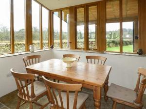 uma mesa de madeira e cadeiras num quarto com janelas em Lane Foot Cottage em Lancaster