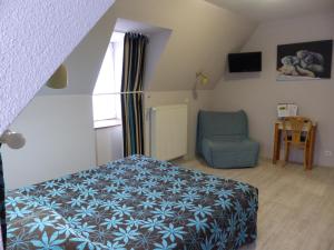 sypialnia z łóżkiem i niebieskim krzesłem w obiekcie Hotel Le Progrés Dorlotel w mieście Mont-Dore