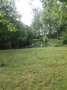 um campo de relva com um lago ao fundo em Chez les Dom’s em Sainte-Cécile