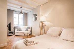 a white bedroom with a bed and a chair at DIFY Seguin - Confluence / Perrache in Lyon