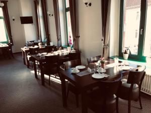 a dining room with wooden tables and chairs and windows at Zum Kaiserlichen Postamt in Parchim
