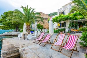 a group of chairs and umbrellas next to the water at Villa Kukuljica in Zaton