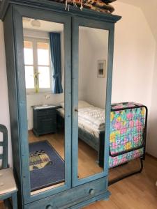 a cabinet with a mirror in a room with a bed at Refugium Raabenhorst im Landhaus am Haff in Stolpe auf Usedom