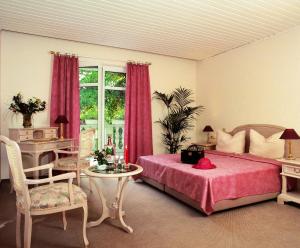 a bedroom with a bed and a table and a window at Hammers Landhotel GmbH in Teltow