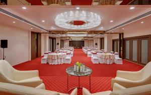 un salón de banquetes con mesas y sillas blancas y una lámpara de araña en The Fern, Kolhapur, en Kolhapur