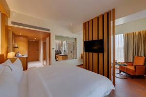 Un dormitorio con una cama blanca y una sala de estar. en The Fern, Kolhapur, en Kolhapur