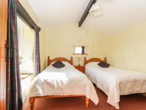a bedroom with two beds and a window at Bowling Green Cottage in Redruth