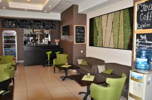 un restaurante con sillas y mesas verdes y un bar en Hills Hotel апарт-отель, en Moscú