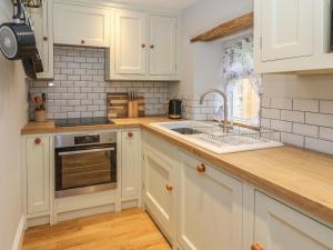 uma cozinha com armários brancos e um lavatório em 5 Bank Cottage em Lancaster