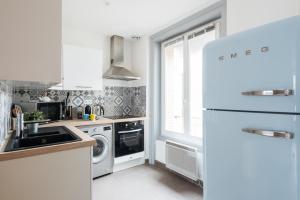 a white kitchen with a sink and a refrigerator at DIFY Cosy - Centre Ville in Lyon