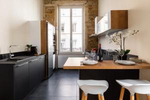 a kitchen with black cabinets and white stools at DIFY Lumière - Masséna in Lyon