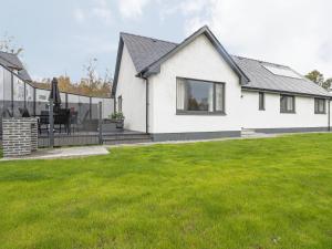 een wit huis met een terras en een tuin bij Emsa House in Spean Bridge