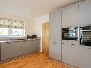 a white kitchen with white cabinets and a window at Emsa House in Spean Bridge