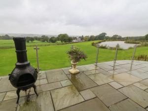 einen Kamin auf einer Terrasse mit einer Blumenvase in der Unterkunft Nicky Nook Lodge in Preston