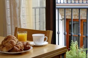 a table with a plate of pastries and a cup of orange juice at Apartamentos Turísticos Centro in Granada