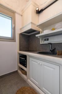 una cocina con armarios blancos y fregadero en Luxurious stoudio in Mandrakia 1 en Mandrakia