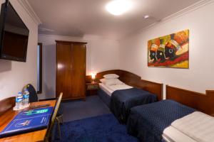 a hotel room with two beds and a table and a desk at Atlanta Budget Darmstadt in Darmstadt