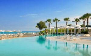 a swimming pool with chairs and umbrellas and the ocean at Capovaticano Resort Thalasso Spa in Capo Vaticano
