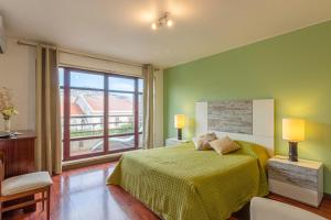 a green bedroom with a bed and a large window at Arriaga Marina Club Apartament in Funchal