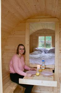 a woman sitting at a table in a wooden cabin at Helshovens wijnvat in Borgloon