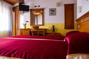 a bedroom with a red bed and a mirror at Hotel Ristorante Centrale in Rovere Veronese
