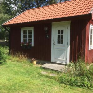 um barracão vermelho com uma porta branca e uma janela em Stensholms Trädgård em Nässjö
