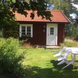 zwei weiße Stühle vor einem kleinen Haus in der Unterkunft Stensholms Trädgård in Nässjö