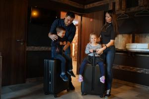 una familia con dos hijos sentados en maletas en Aparthotel MyCologne en Colonia