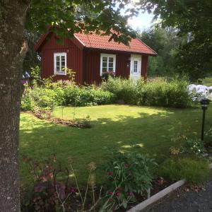 a small red house in a yard with a grass yard at Stensholms Trädgård in Nässjö