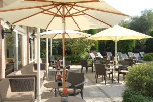 eine Terrasse mit Tischen, Stühlen und Sonnenschirmen in der Unterkunft Hotel the Wigwam in Domburg