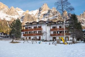 a large building in the snow with a mountain at Relais Clubresidence in San Martino di Castrozza