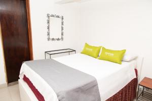 a bedroom with a white bed with green pillows at Ayenda 1131 Casa Valencia in Manizales
